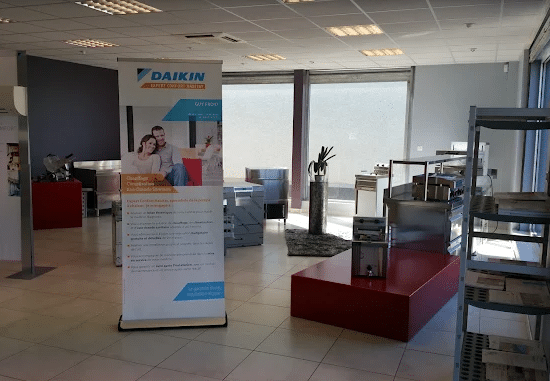 Roll-up Daikin Expert Confort Maîtrise avec couple souriant, annonçant chauffage et climatisation, dans un showroom avec équipements inox.